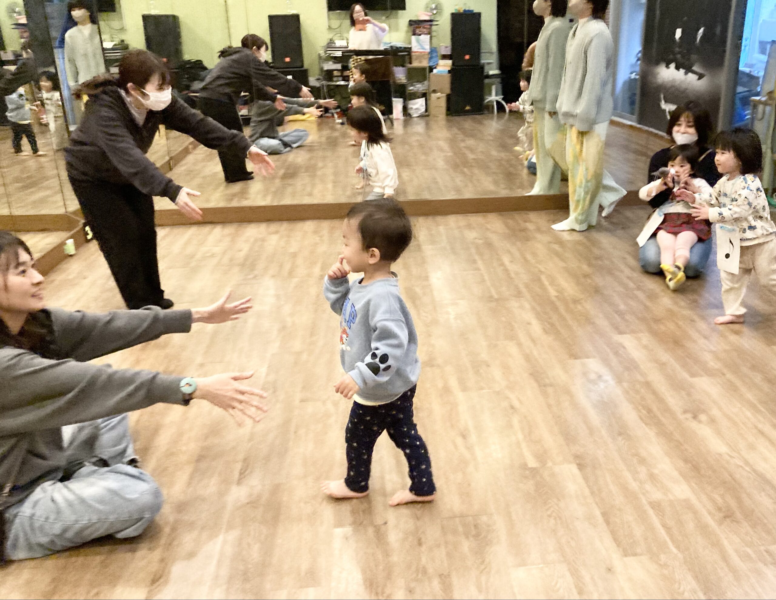 ママが両手を広げているところへ歩いていく子ども。リトミック