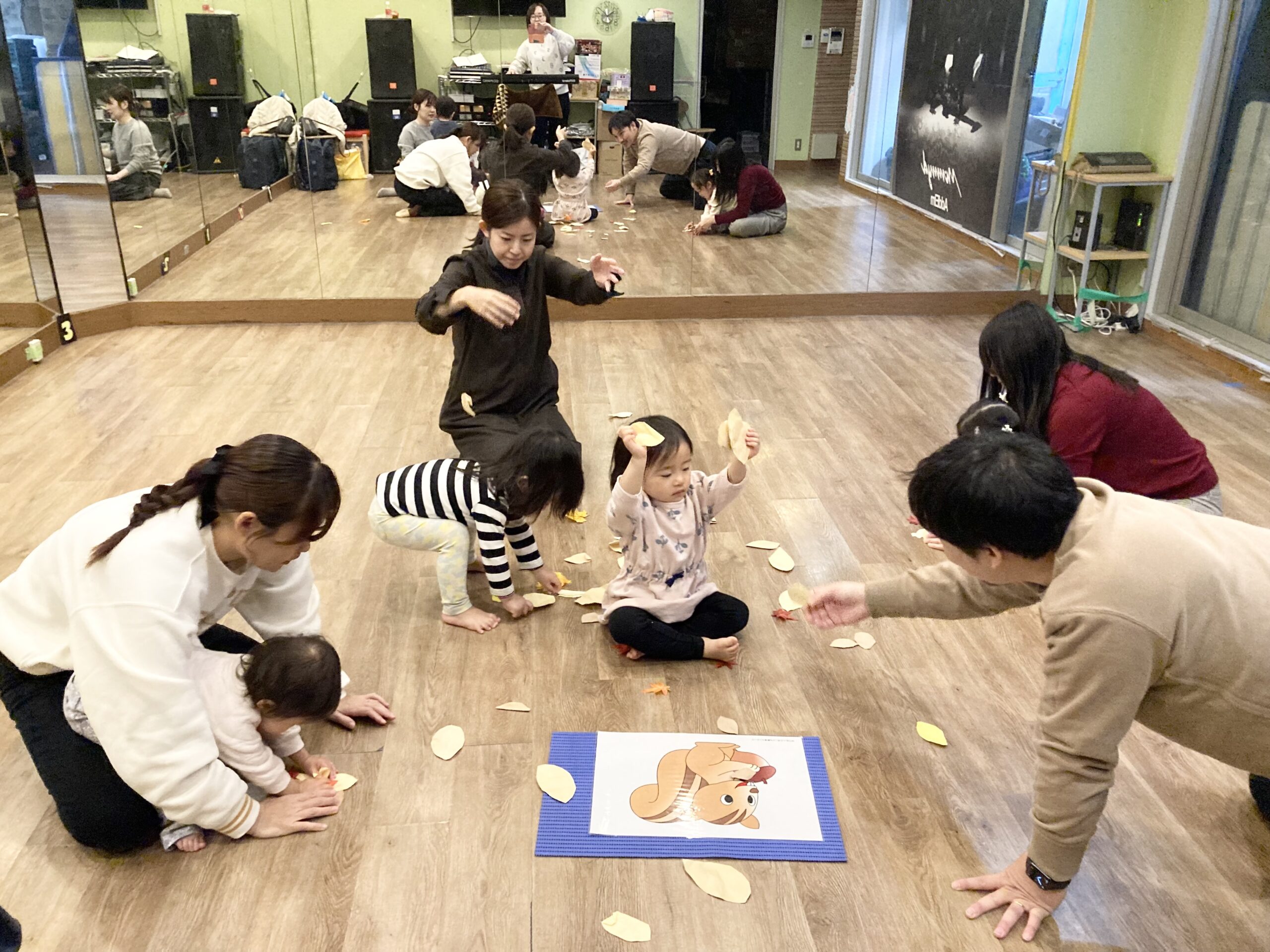 葉っぱを落として季節感を感じるリトミックをしている子どもたちと大人たち