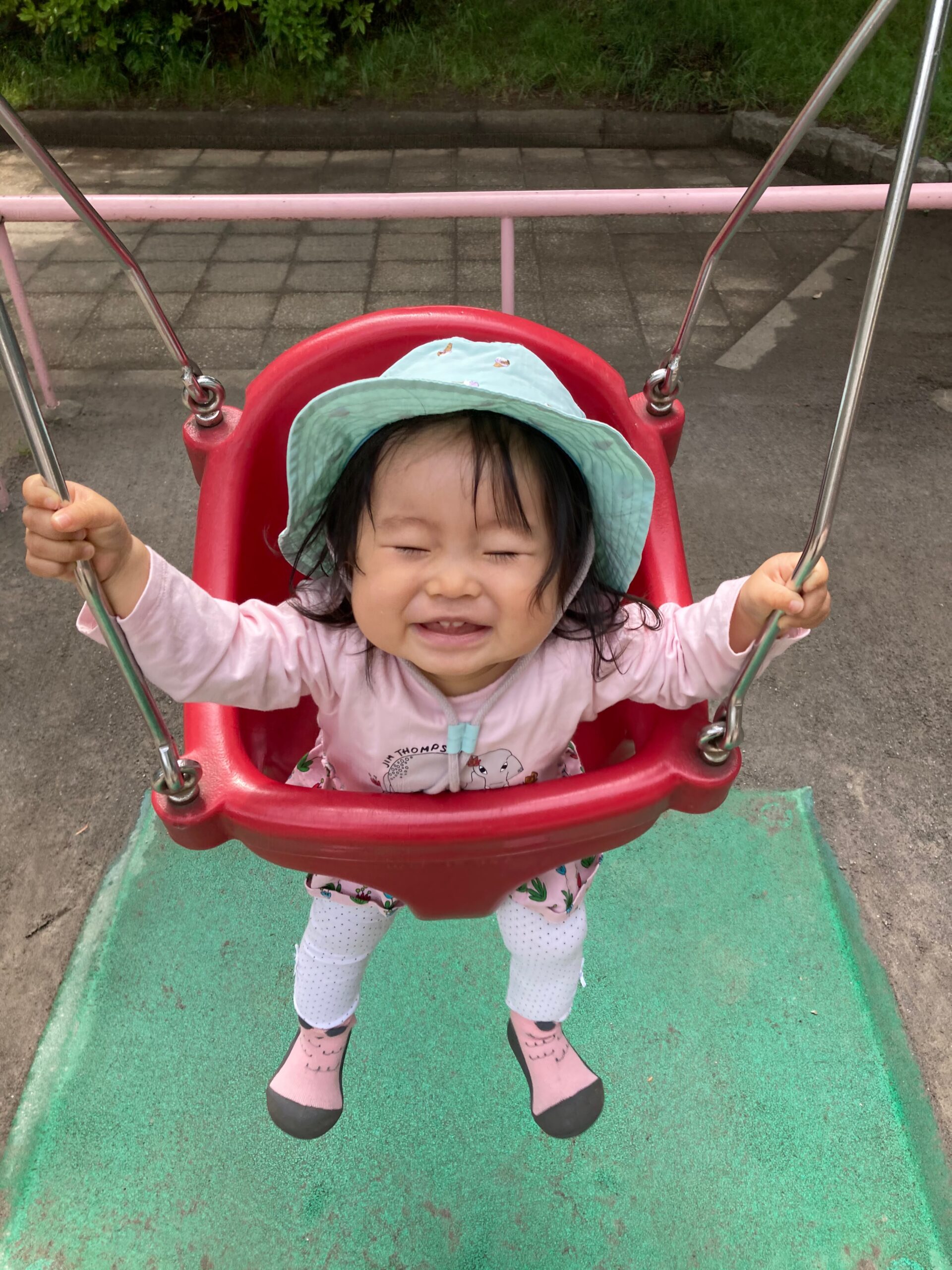 公園の幼児用ブランコに乗って笑ってる赤ちゃん